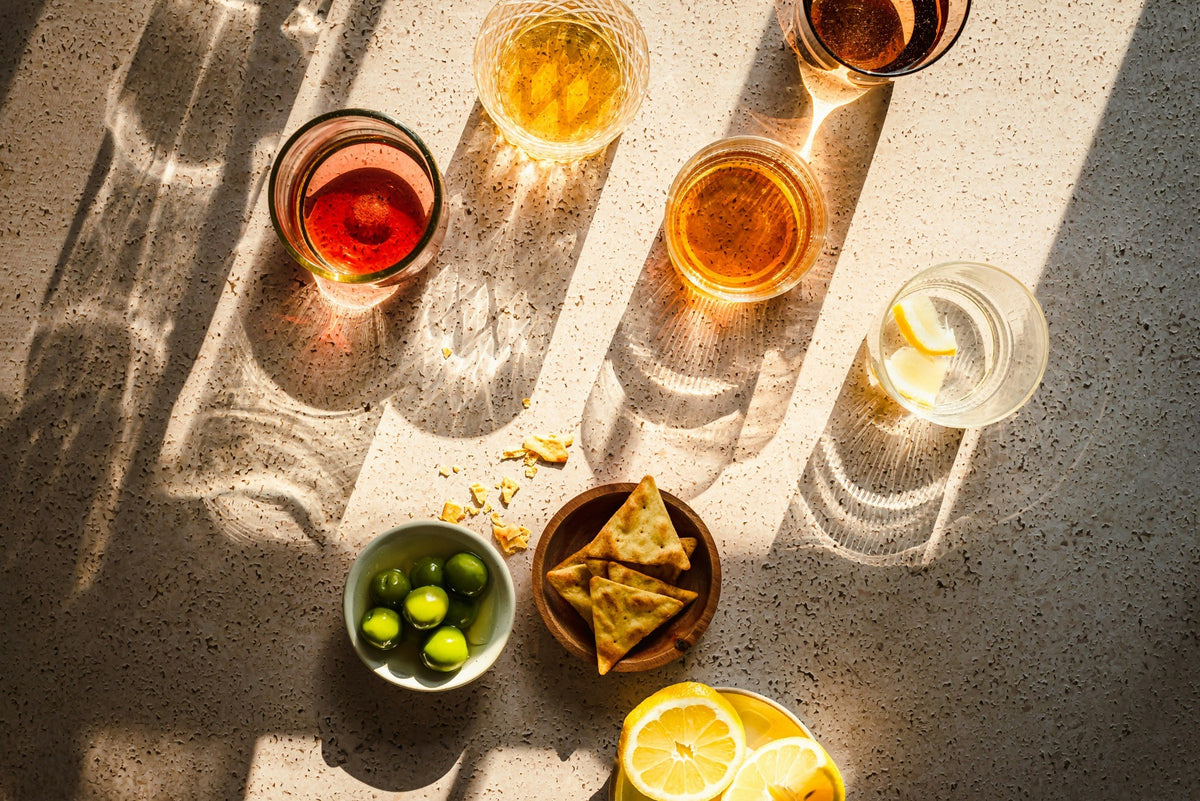 Sunlit aperitivo drinks with green olives, crackers and lemon. Photograph by Natalie Behn.